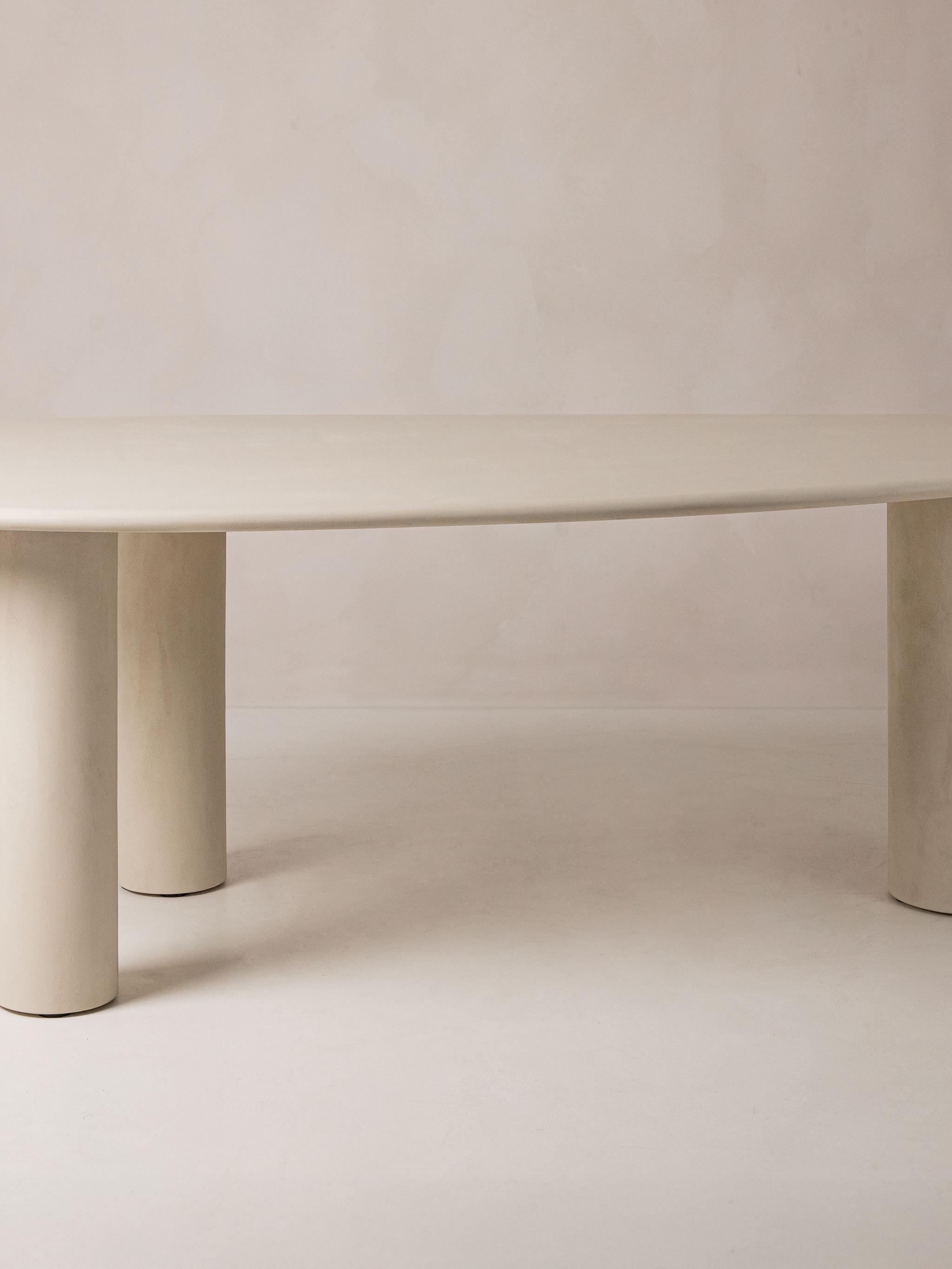 Table de salle à manger Micadoni Mel, plateau ovale sur trois pieds piliers arrondis, beige clair.