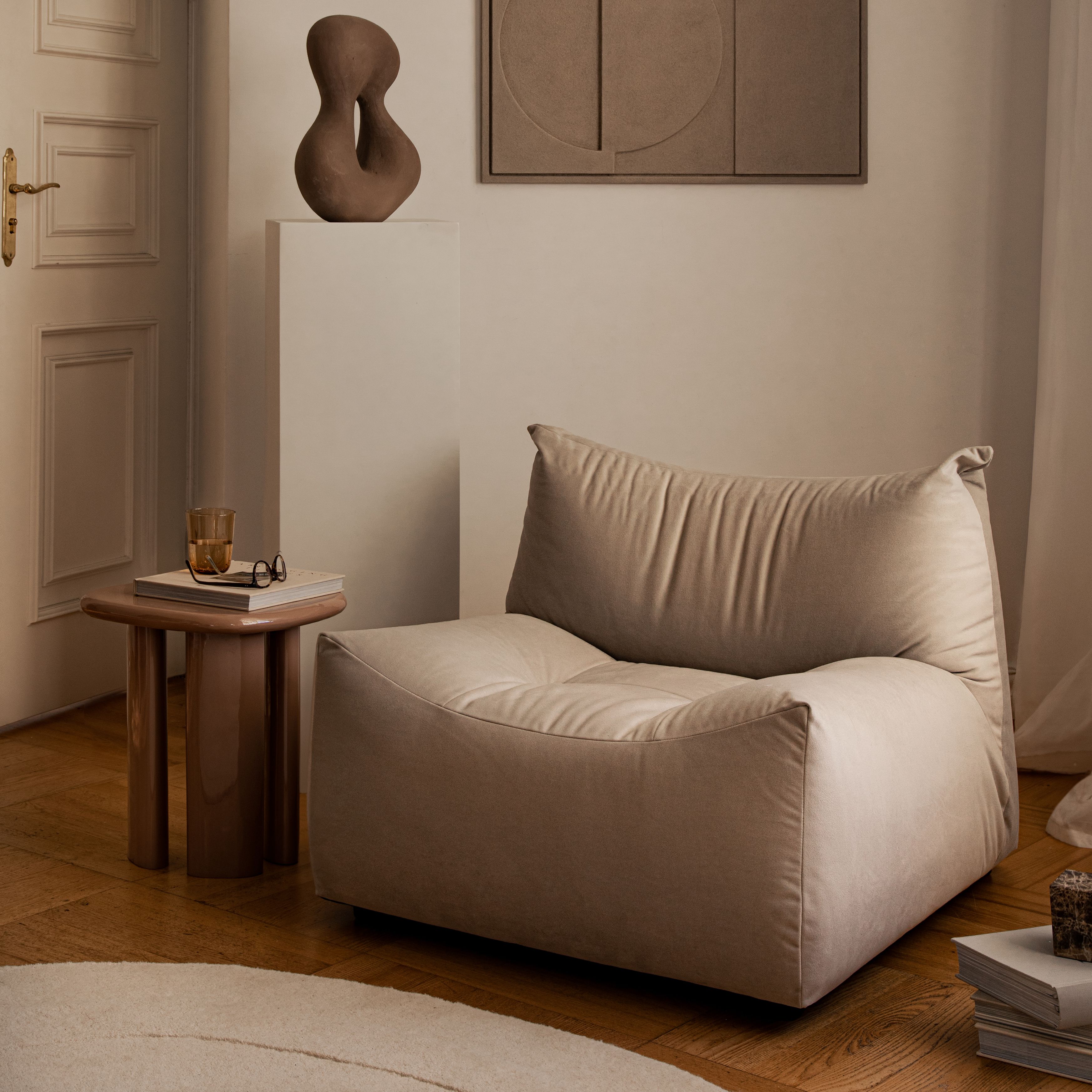 Fauteuil lounge Micadoni avec assise profonde et dossier type coussin, tissu beige, profil bas.