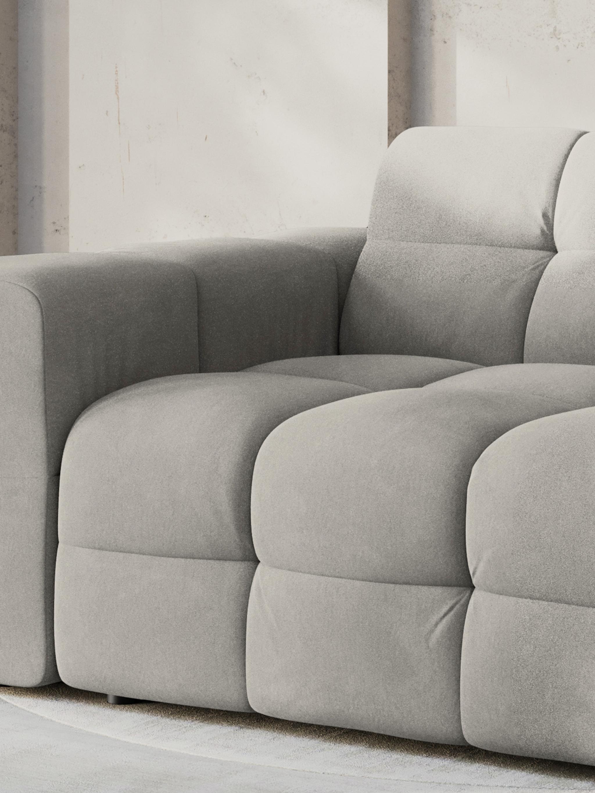 Kendal sofa in soft grey fabric with tufted cushions and structured armrests, offering modern comfort and style.