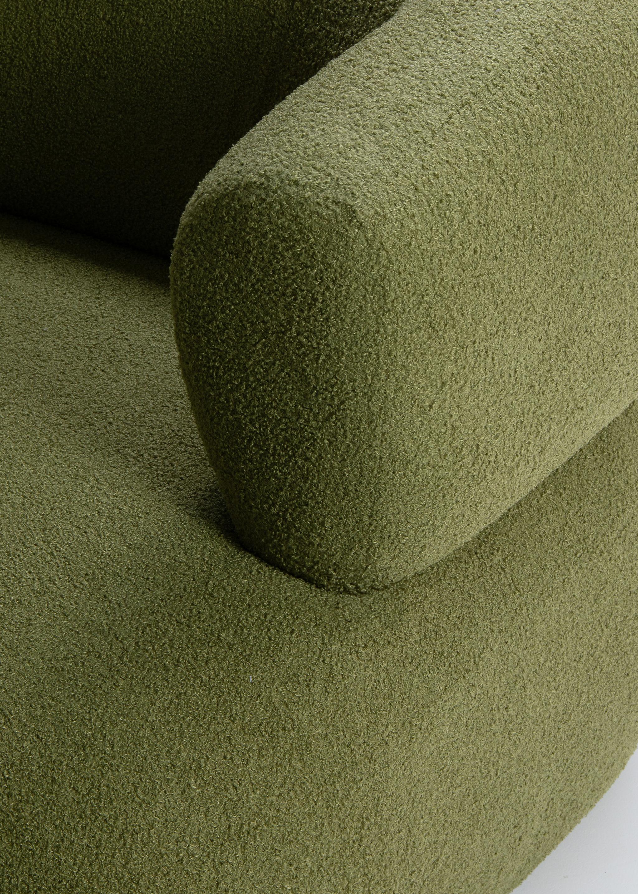 Gros plan du fauteuil Jenny en bouclé vert avec dossier arrondi et accoudoir sculpté – mobilier Micadoni