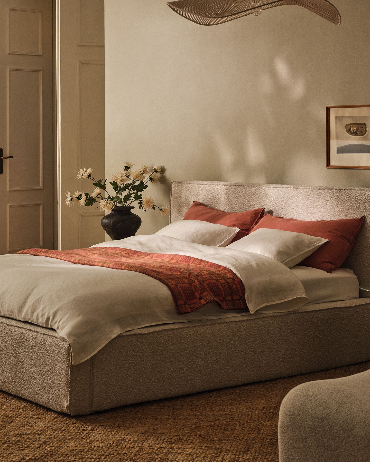 Table ronde Micadoni à piétement central, finition blanche mate, avec livre ouvert, tasses en céramique et chaise à accoudoirs en bois.