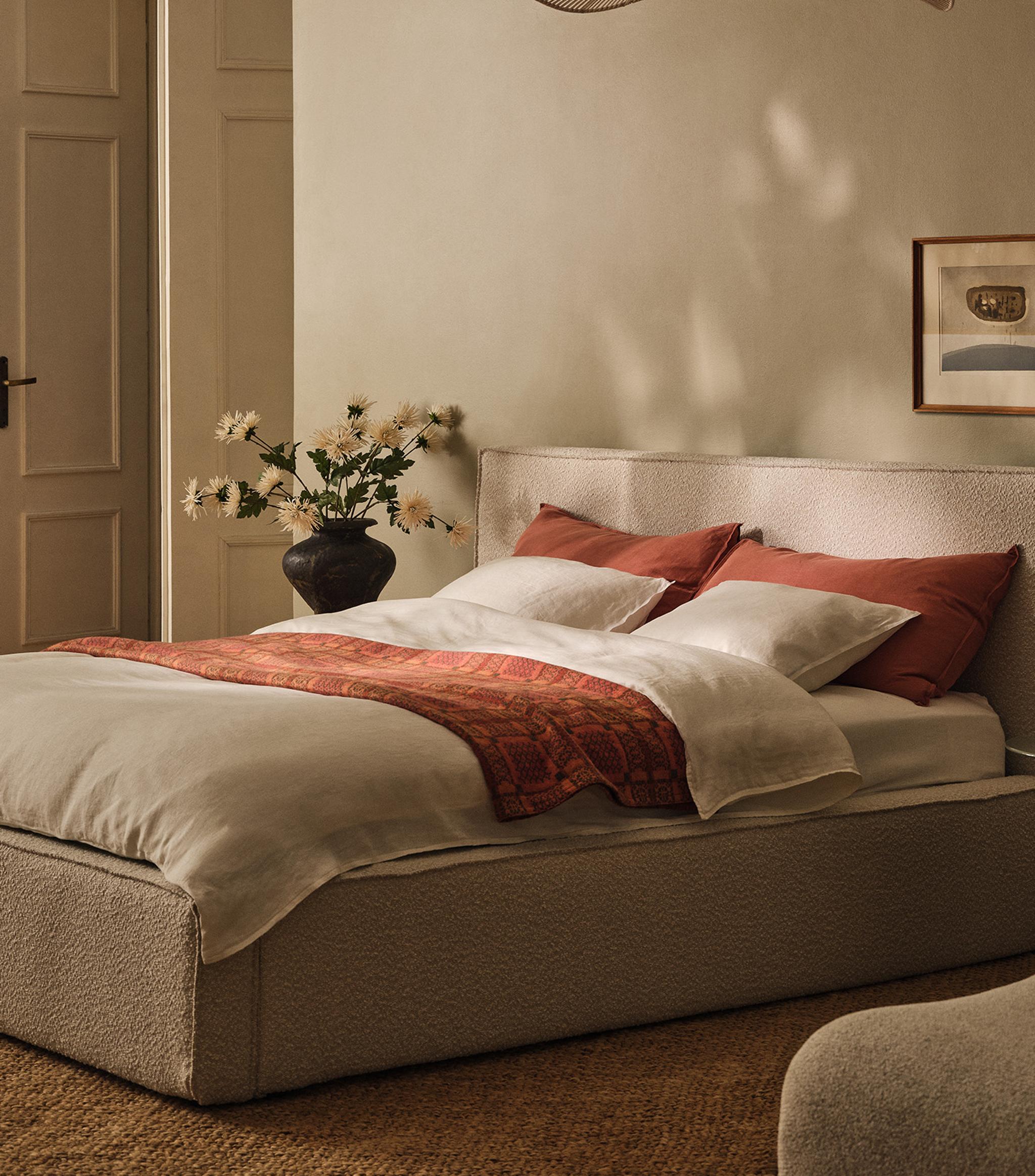 Table ronde Micadoni à piétement central, finition blanche mate, avec livre ouvert, tasses en céramique et chaise à accoudoirs en bois.