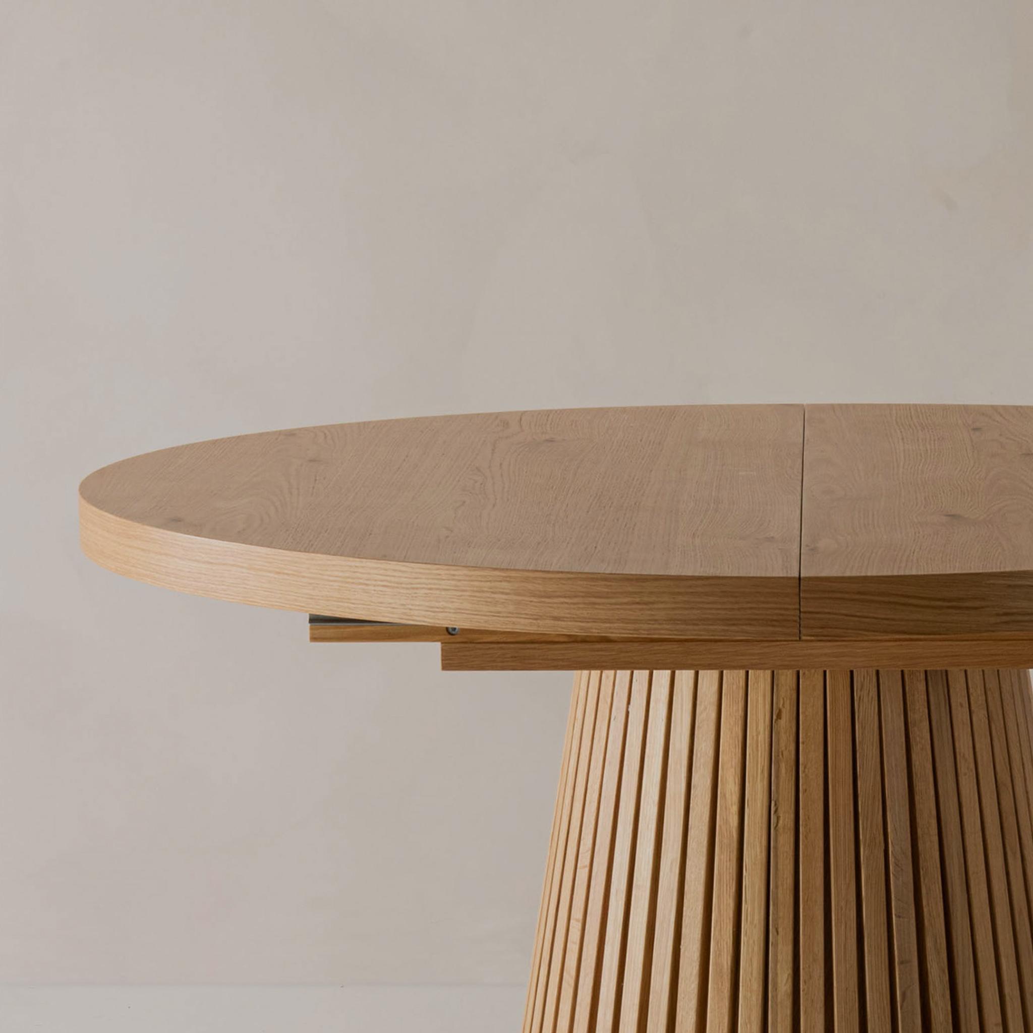 Collection de tables en bois Micadoni, gros plan sur plateau rond extensible et base striée.