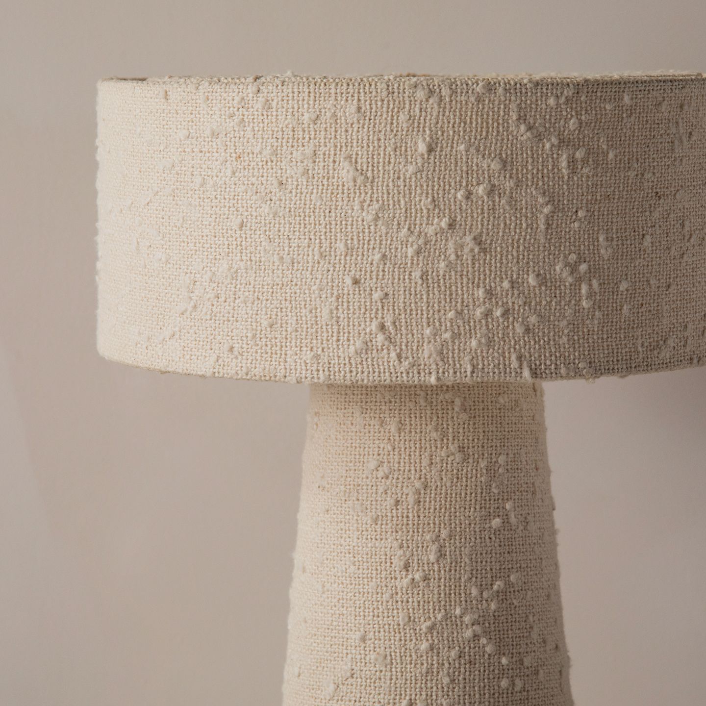 Fauteuil lounge Micadoni avec assise profonde et dossier type coussin, tissu beige, profil bas.