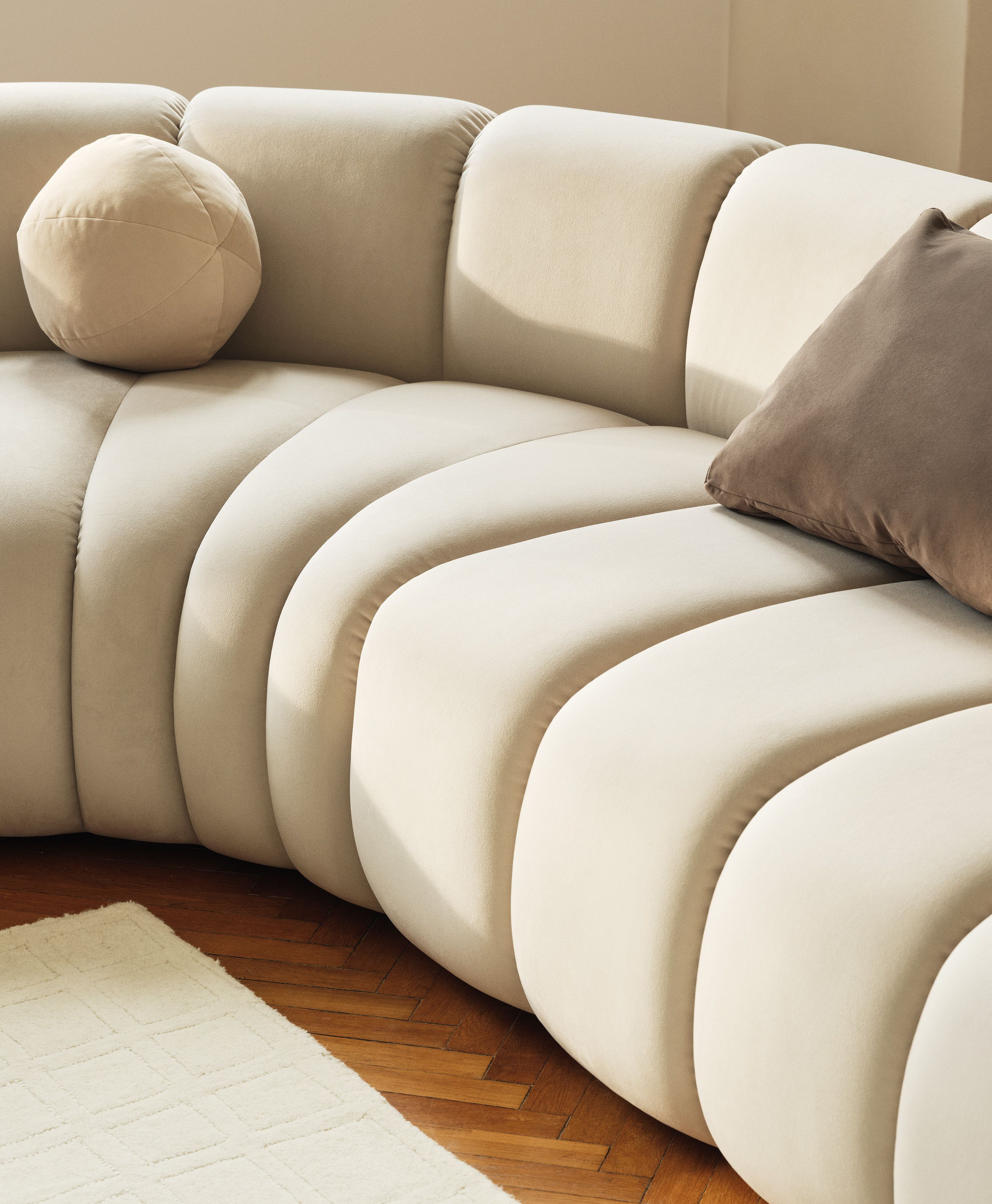 Gros plan du canapé modulaire Lupine en tissu crème avec surpiqûres verticales et courbes sculpturales – mobilier Micadoni