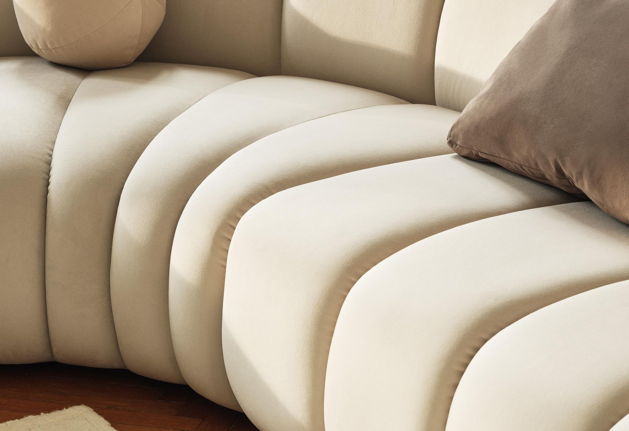 Gros plan du canapé modulaire Lupine en tissu crème avec surpiqûres verticales et courbes sculpturales – mobilier Micadoni