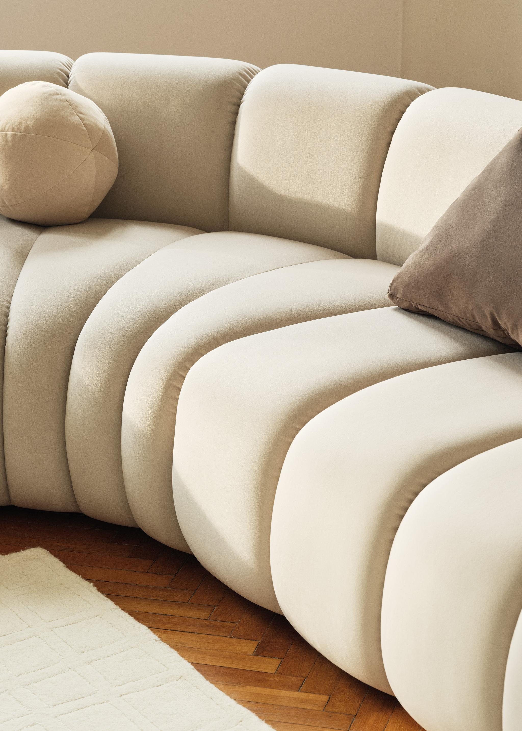 Gros plan du canapé modulaire Lupine en tissu crème avec surpiqûres verticales et courbes sculpturales – mobilier Micadoni