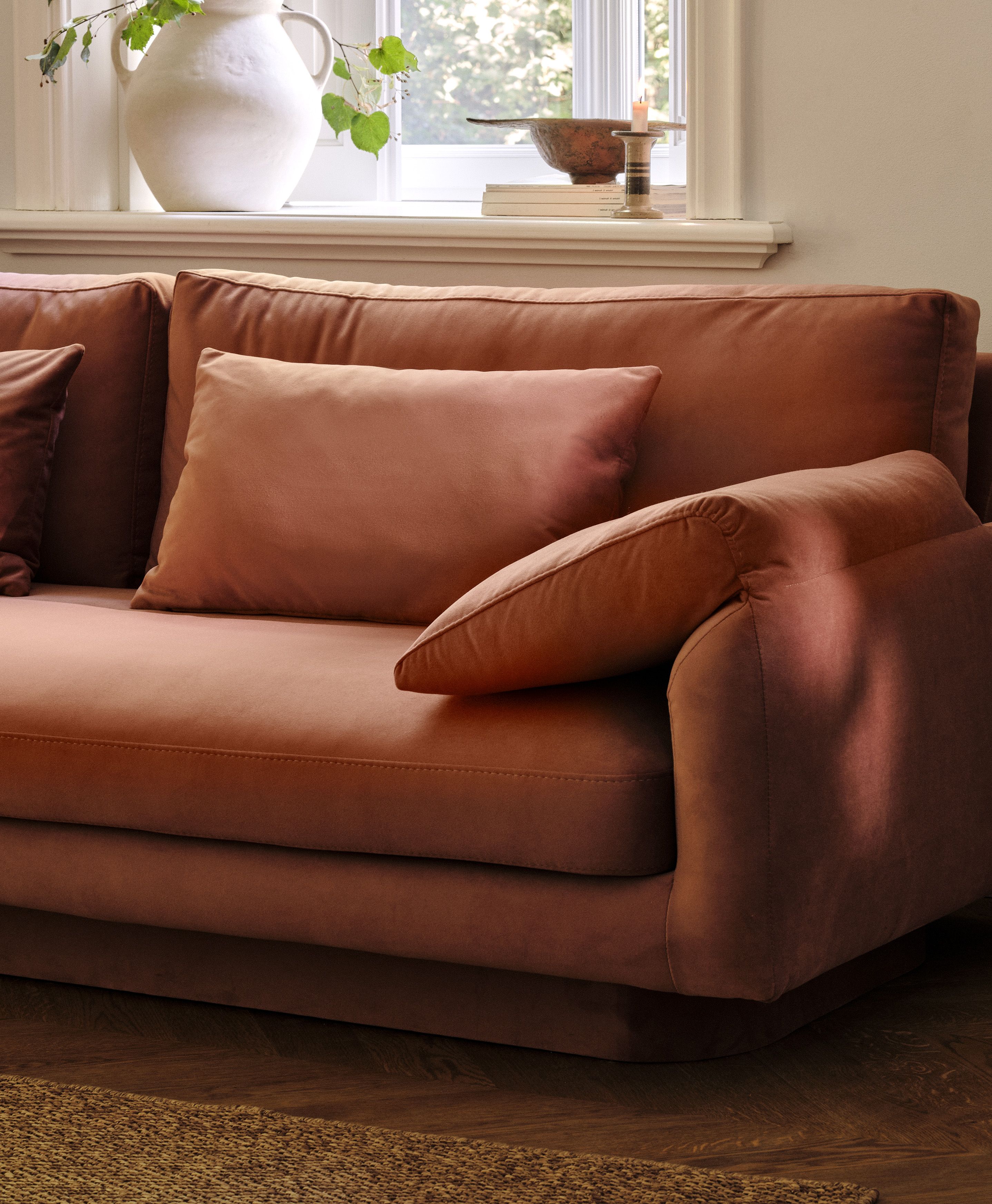 Gros plan du canapé Torino en velours couleur rouille avec accoudoirs larges rembourrés et assise profonde – mobilier Micadoni