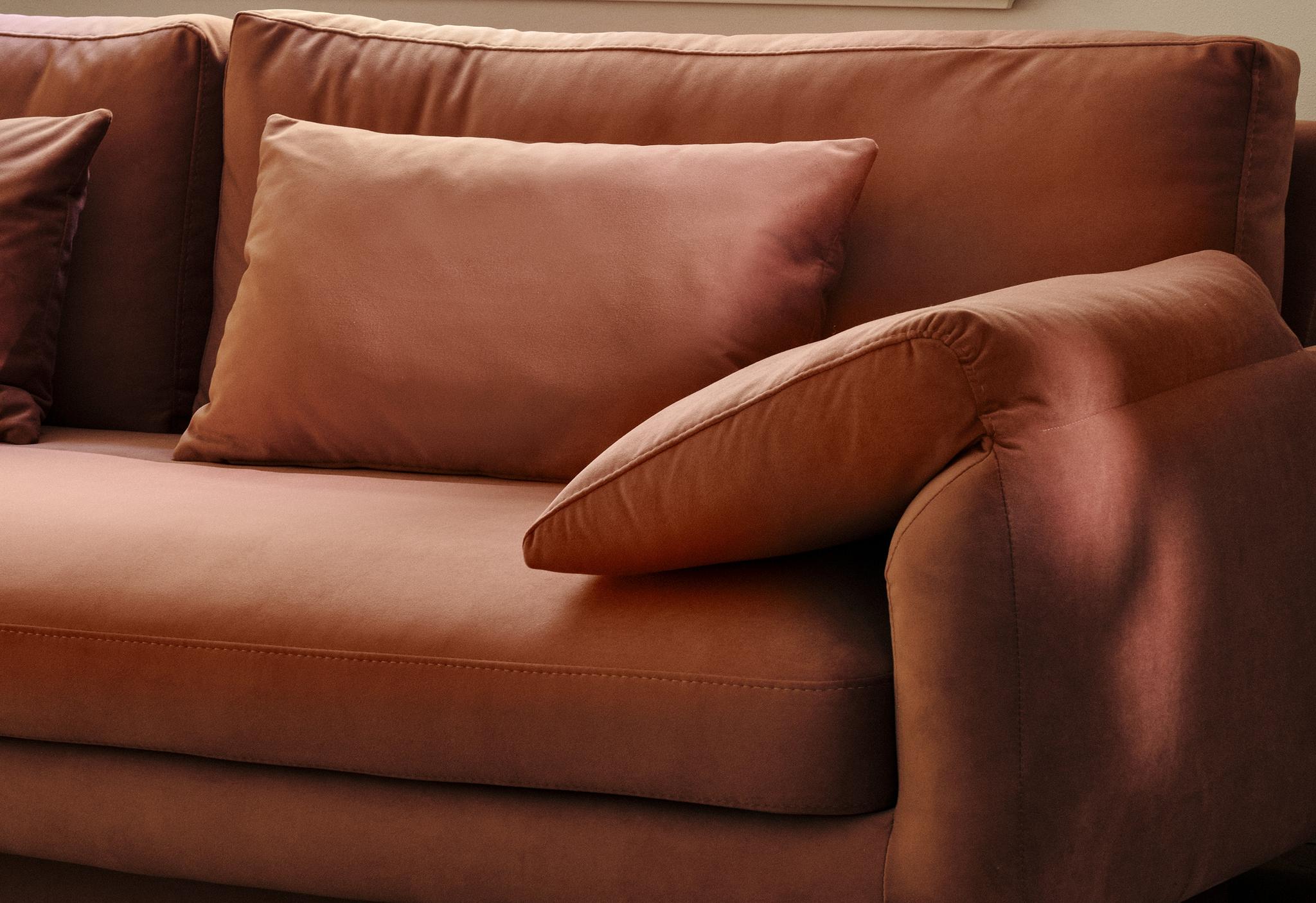 Gros plan du canapé Torino en velours couleur rouille avec accoudoirs larges rembourrés et assise profonde – mobilier Micadoni