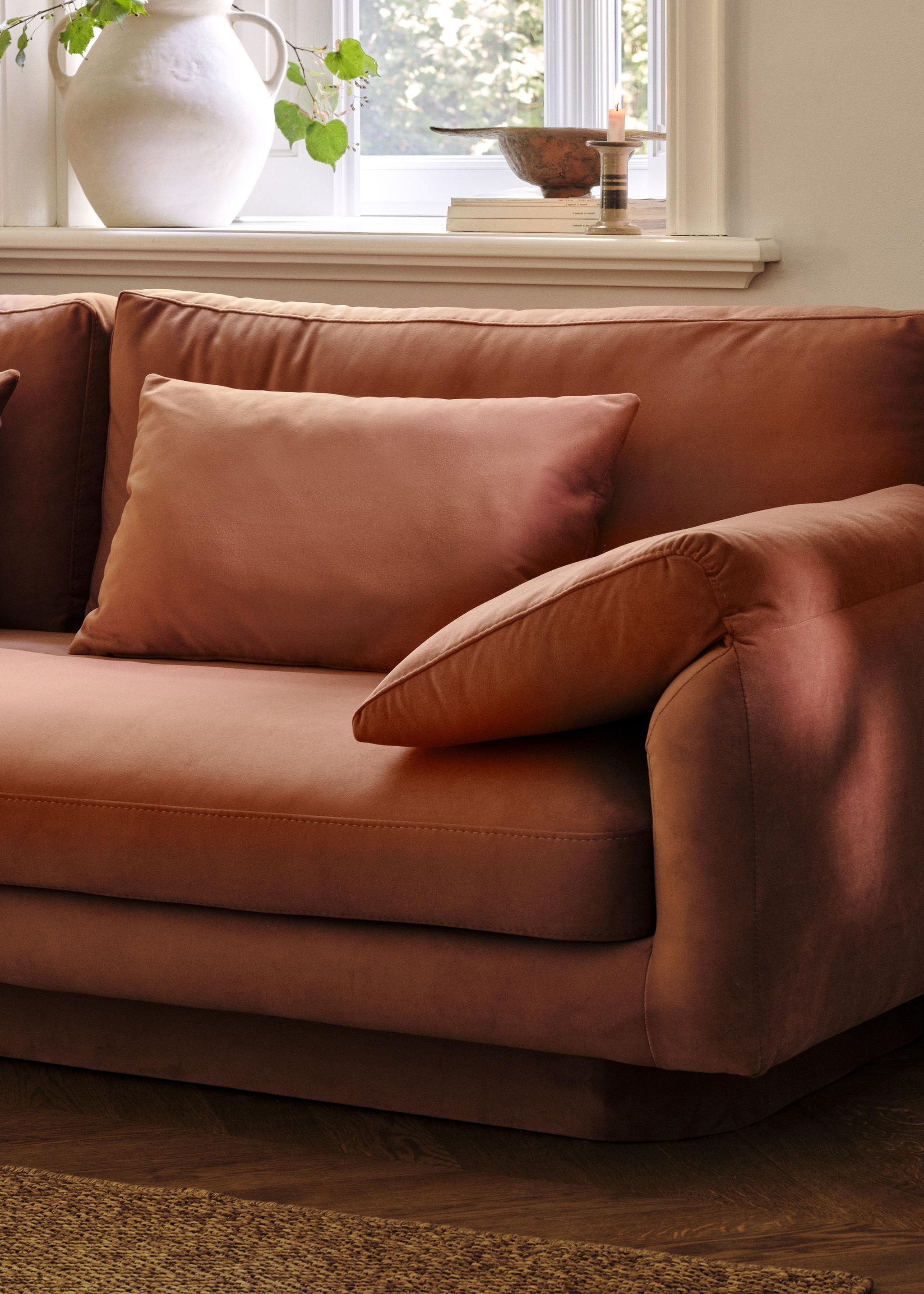 Gros plan du canapé Torino en velours couleur rouille avec accoudoirs larges rembourrés et assise profonde – mobilier Micadoni