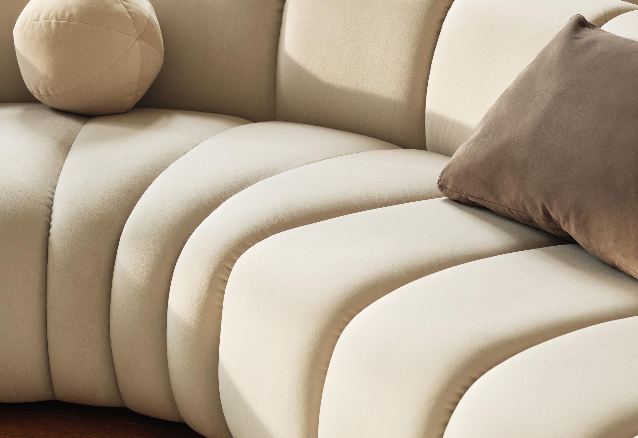 Gros plan du canapé modulaire Lupine en tissu crème avec surpiqûres verticales et courbes sculpturales – mobilier Micadoni
