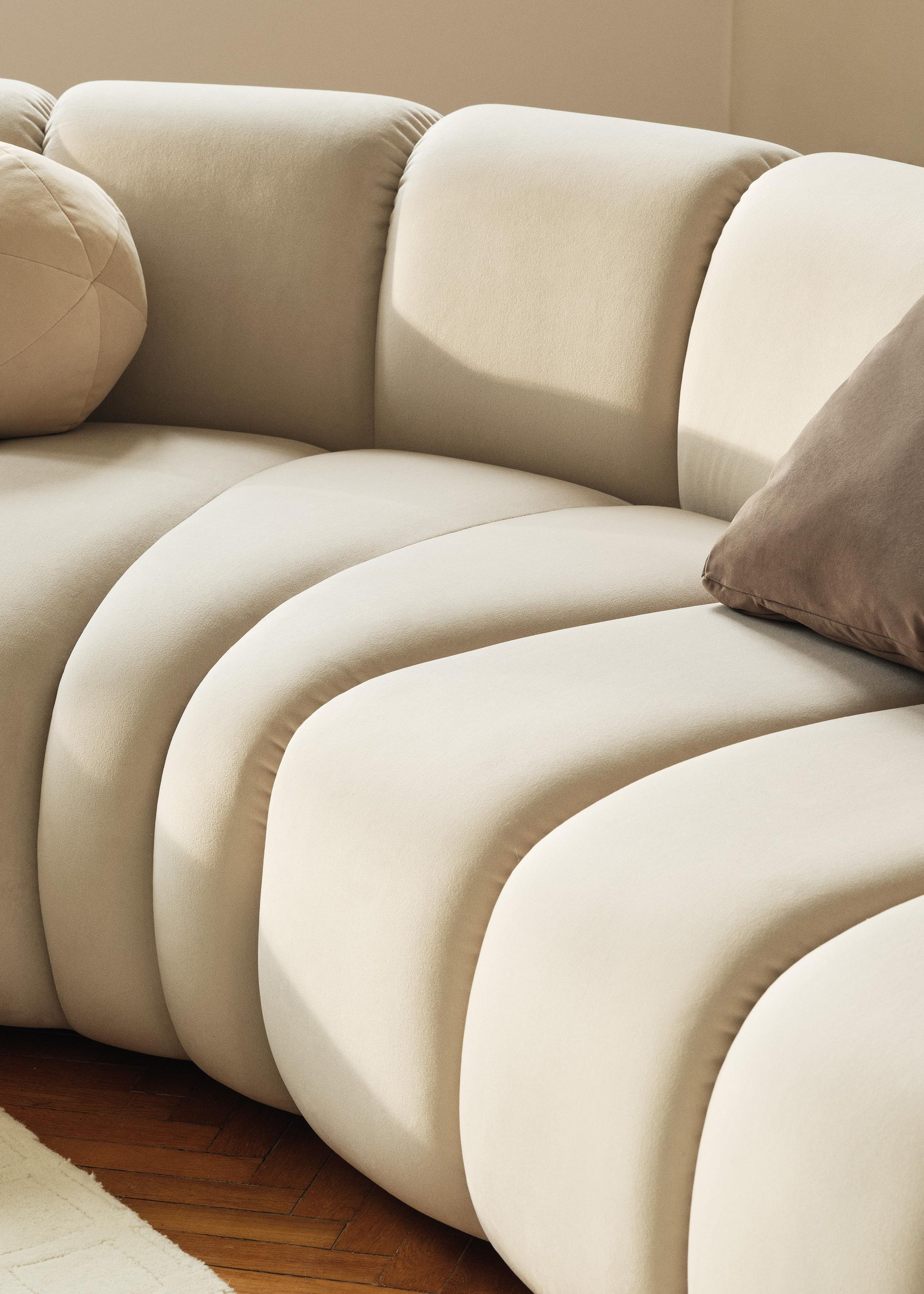 Gros plan du canapé modulaire Lupine en tissu crème avec surpiqûres verticales et courbes sculpturales – mobilier Micadoni