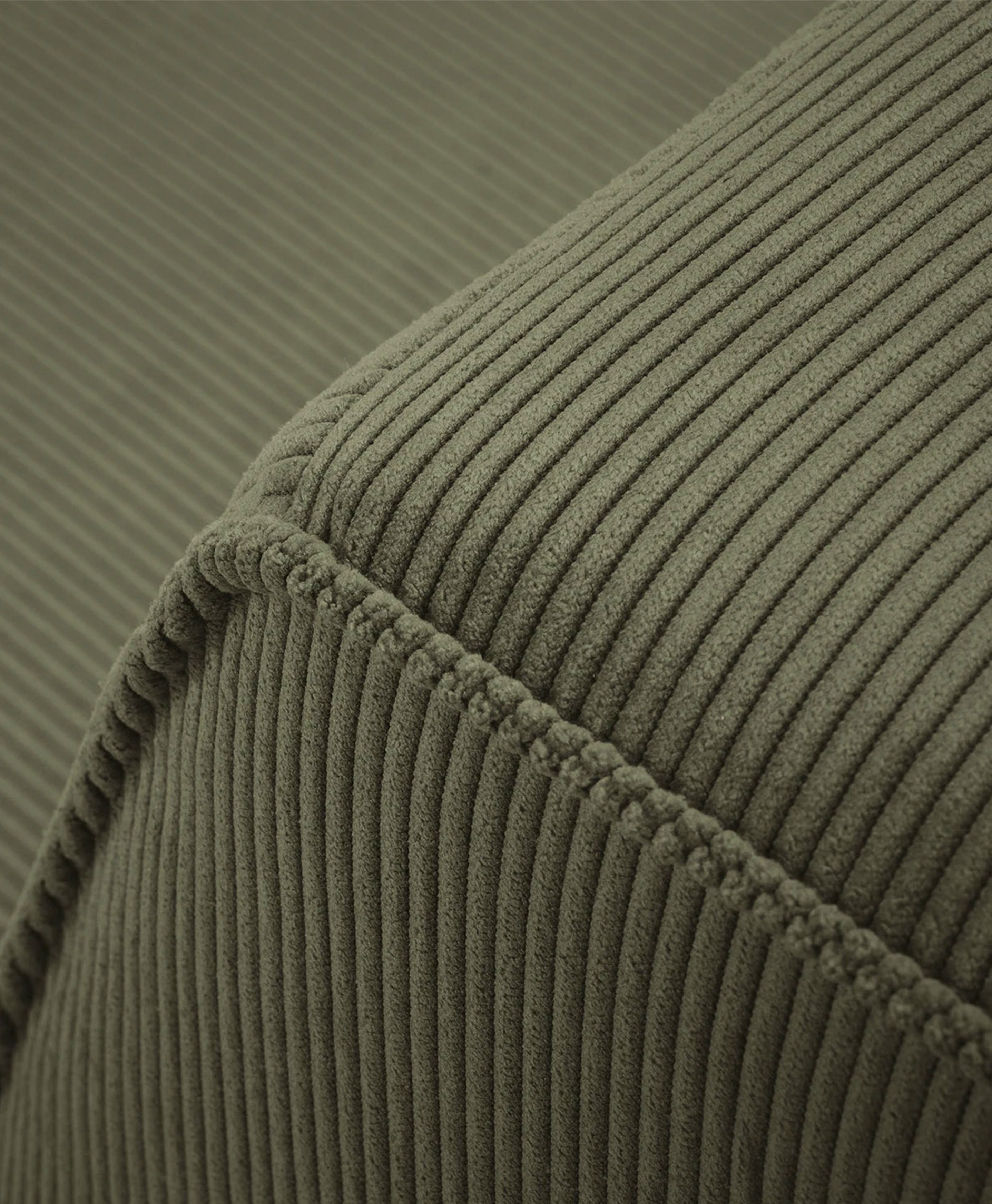 Gros plan du canapé Ruby en tissu côtelé vert olive avec coutures apparentes – mobilier Micadoni