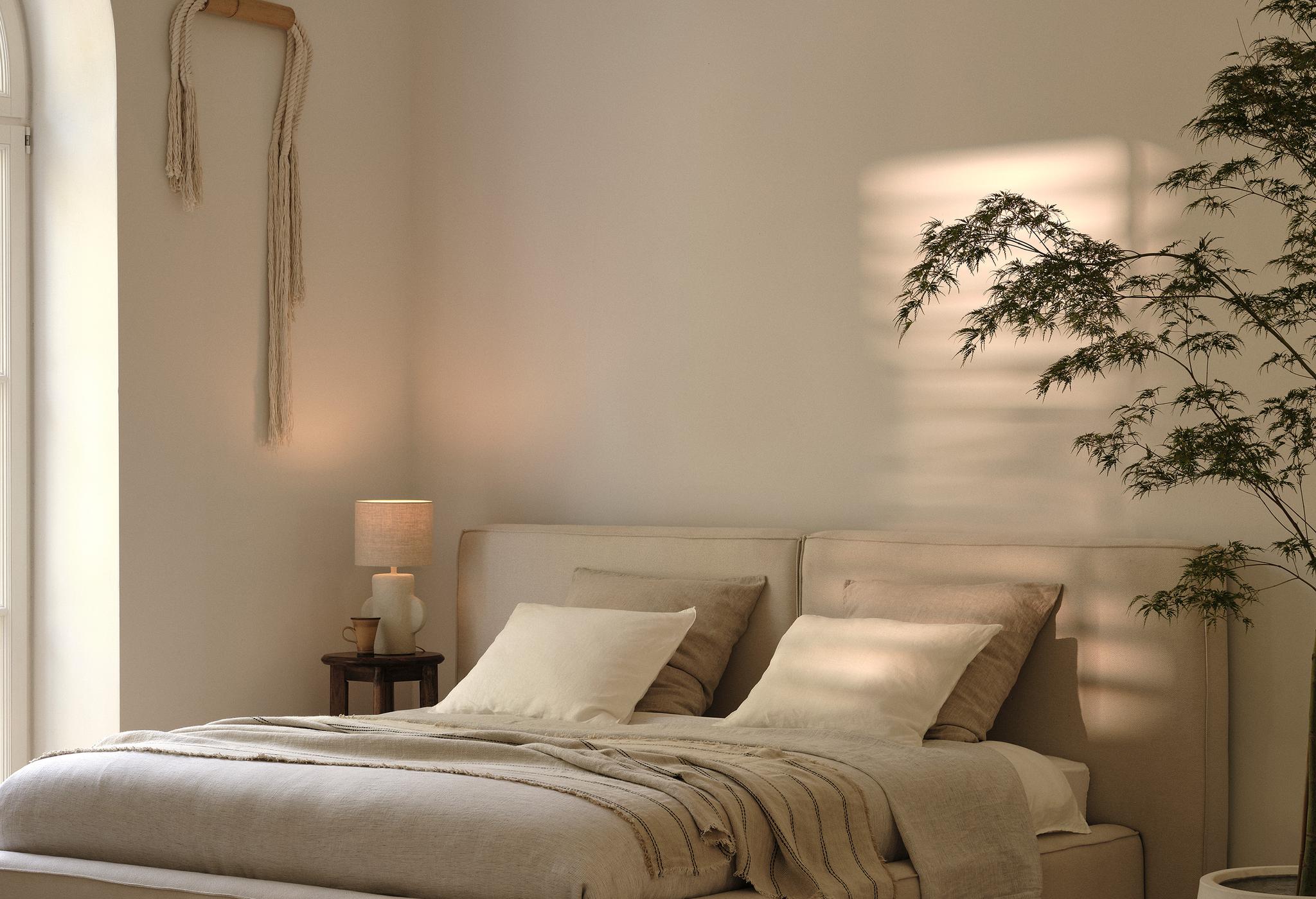 Lit Micadoni capitonné en tissu beige avec tête de lit rembourrée dans une chambre apaisante.