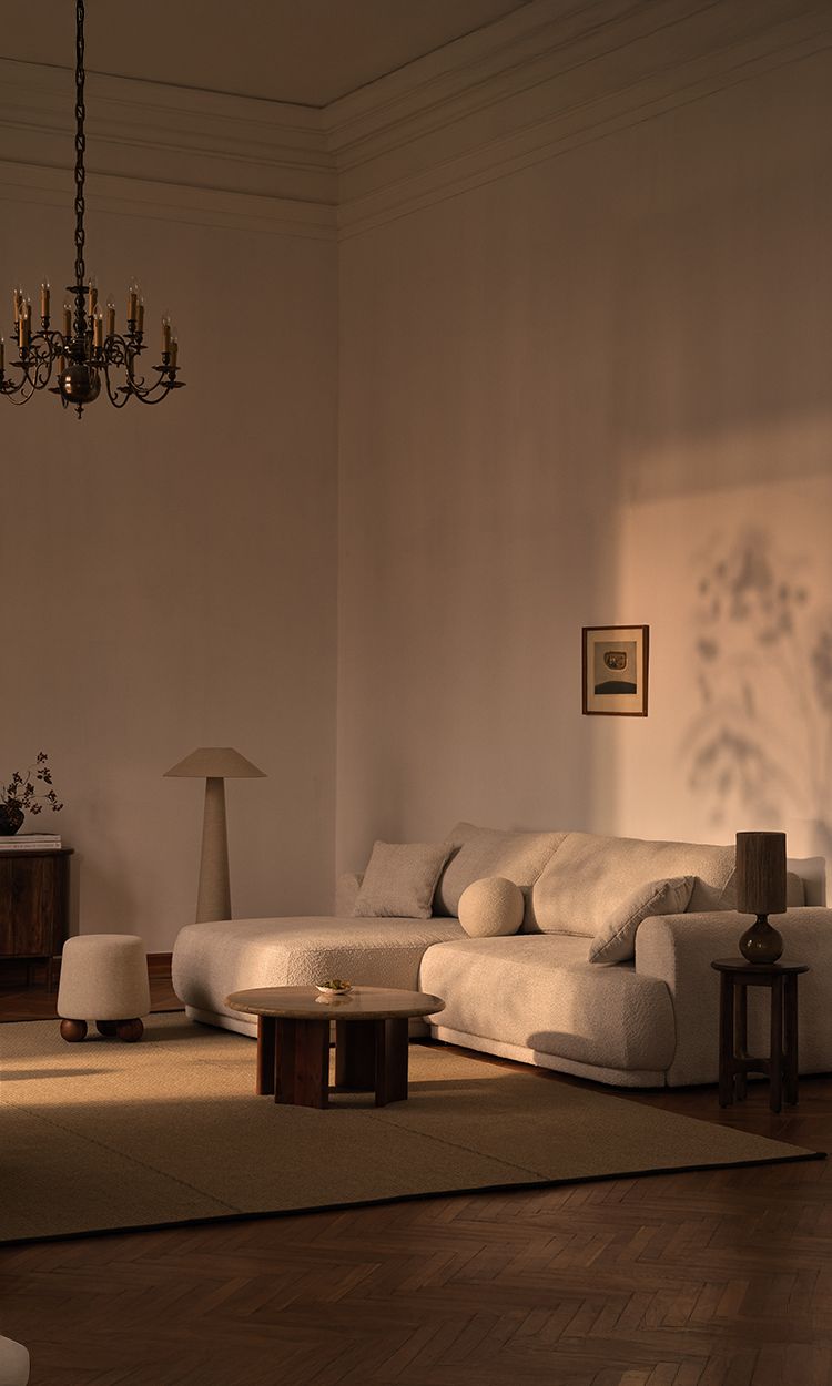 Canapé d’angle Micadoni Ella en bouclé crème, dans un salon minimaliste aux accents bois.