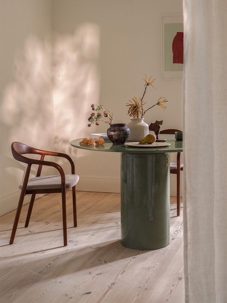 able de repas Micadoni ronde vert olive, piètement colonne laqué, avec chaise Illa en bois courbé et assise beige, pièce baignée de soleil.