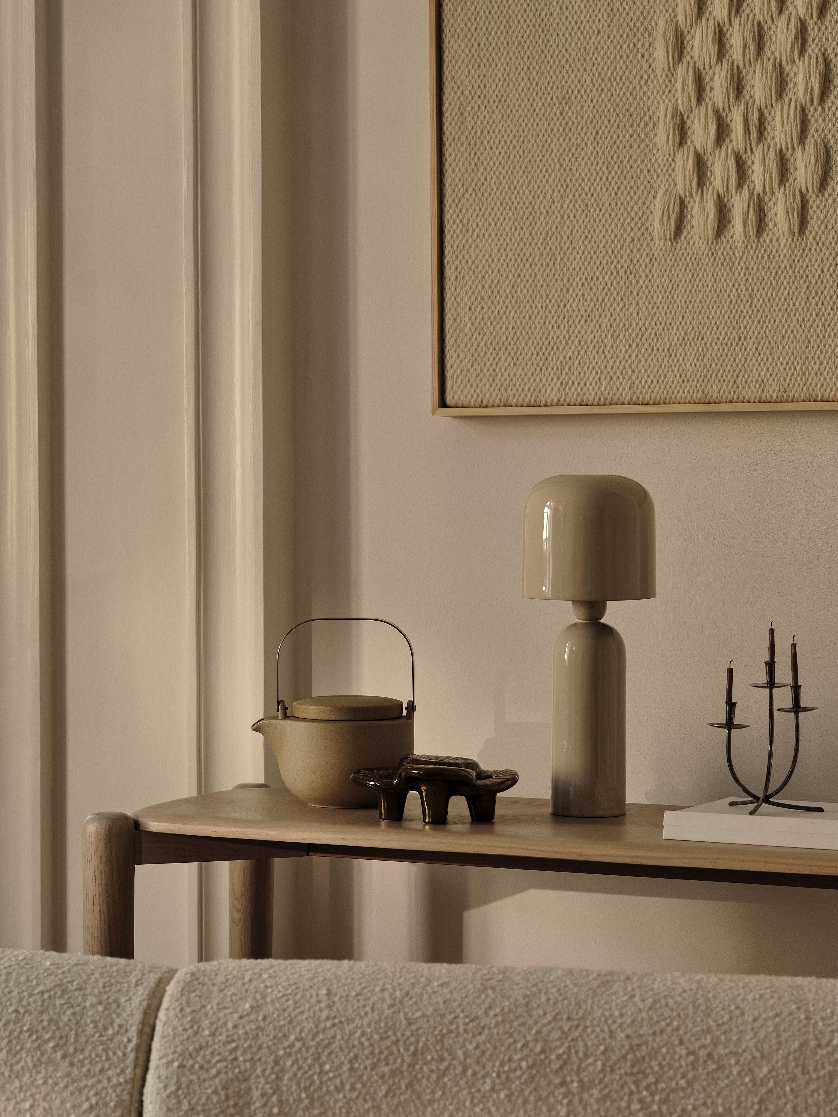 Lampe de table en céramique Micadoni avec théière en grès, plateau sculptural et candélabre métallique sur console en bois, éclairage chaleureux.