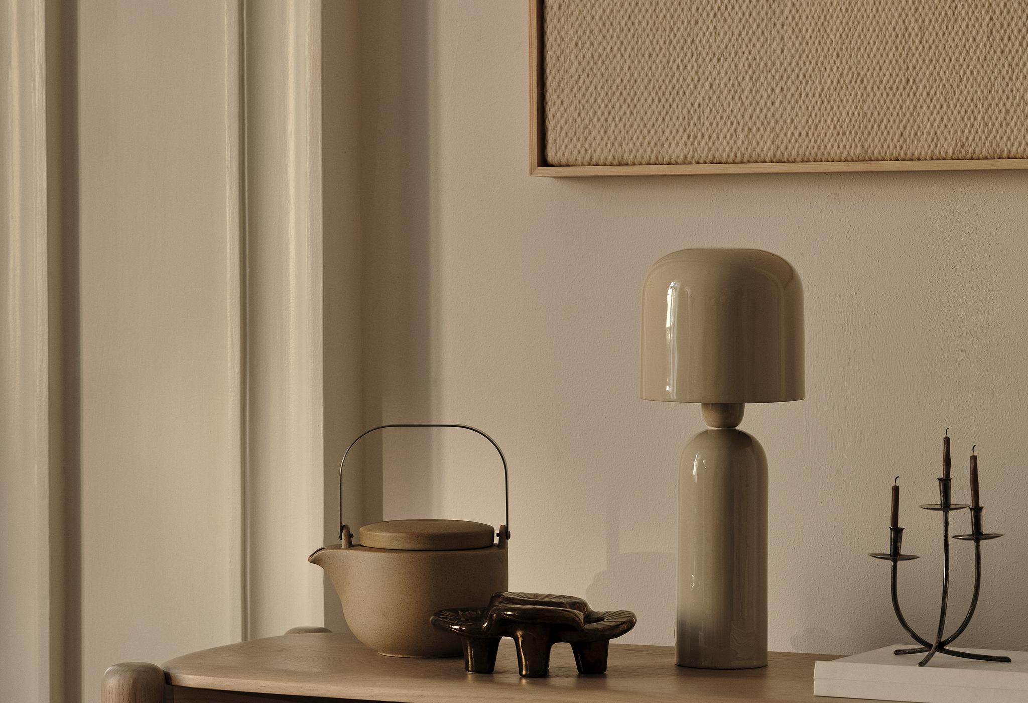 Lampe de table en céramique Micadoni avec théière en grès, plateau sculptural et candélabre métallique sur console en bois, éclairage chaleureux.