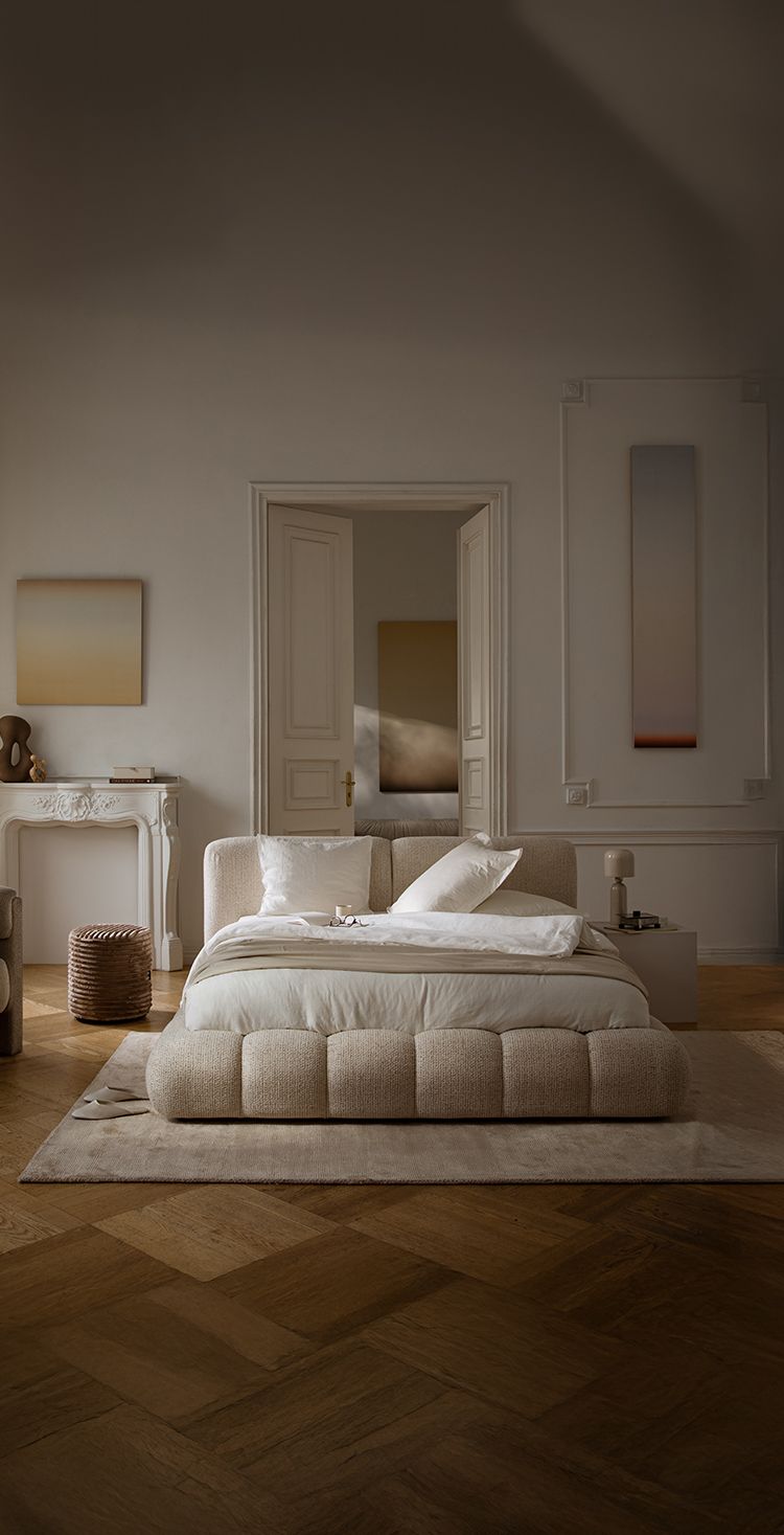 Lit Micadoni Martina avec base capitonnée arrondie et grande tête de lit texturée dans une chambre chaleureuse.