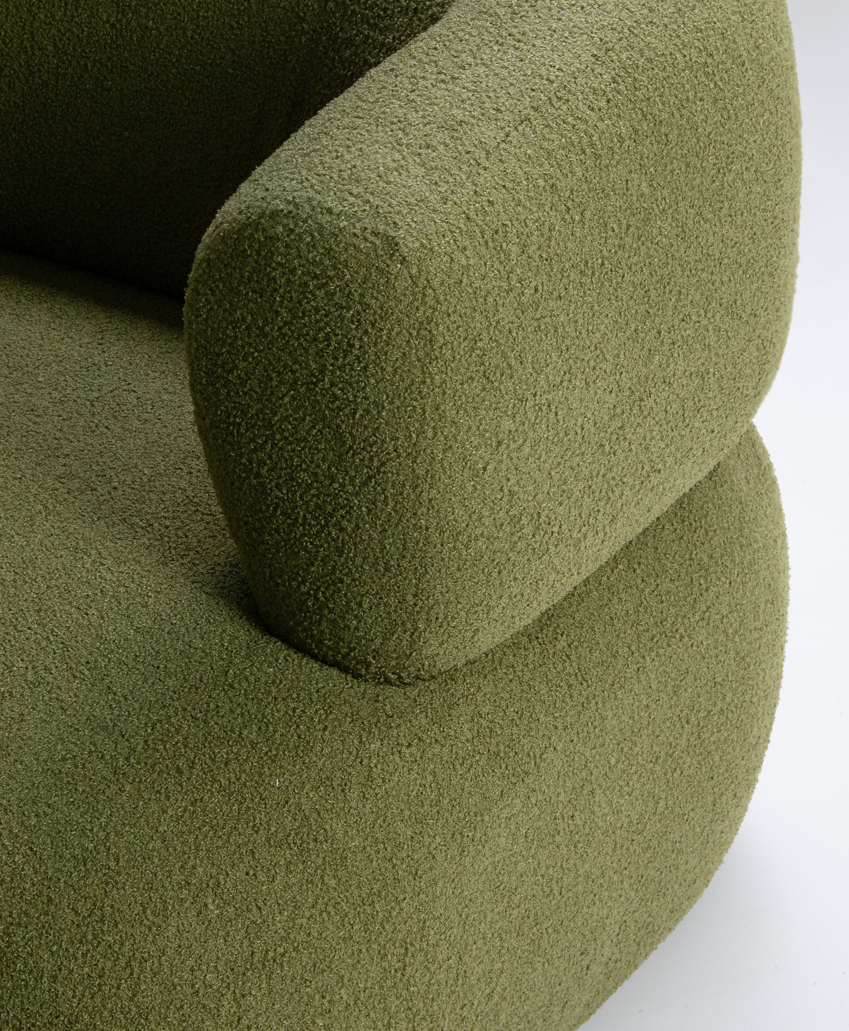 Gros plan du fauteuil Jenny en bouclé vert avec dossier arrondi et accoudoir sculpté – mobilier Micadoni