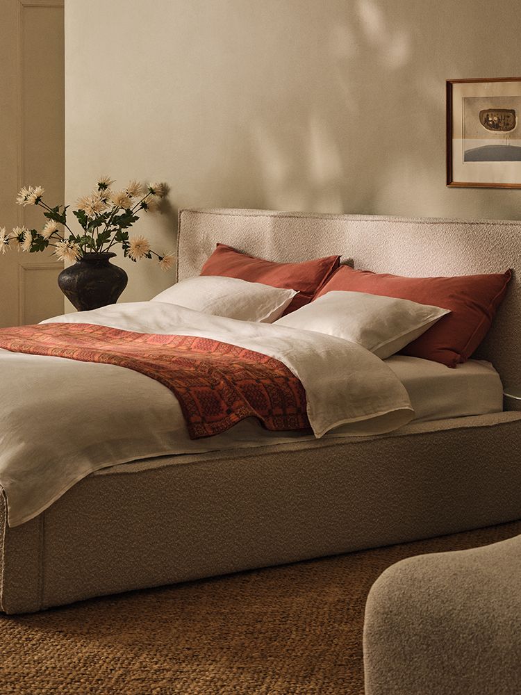 Table ronde Micadoni à piétement central, finition blanche mate, avec livre ouvert, tasses en céramique et chaise à accoudoirs en bois.