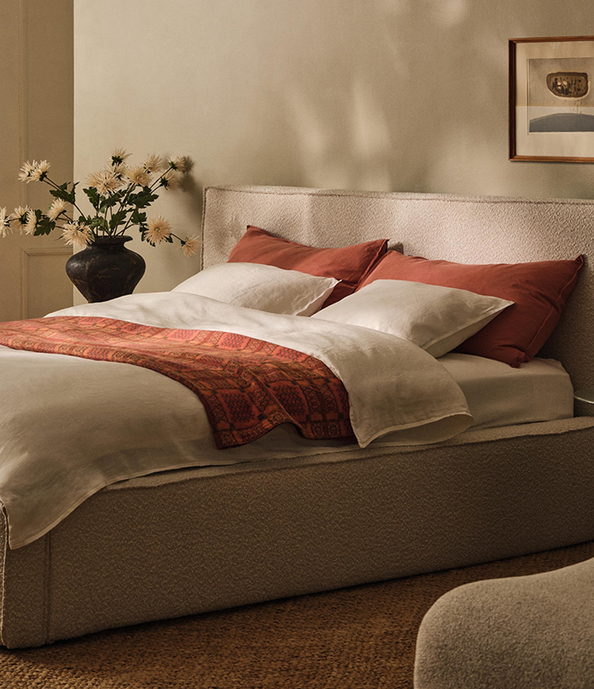 Table ronde Micadoni à piétement central, finition blanche mate, avec livre ouvert, tasses en céramique et chaise à accoudoirs en bois.