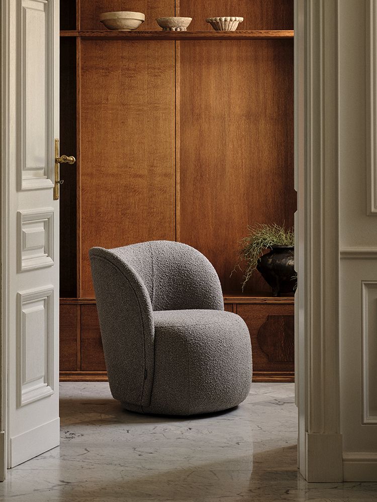 Fauteuil Micadoni aux lignes arrondies, revêtement texturé gris, mis en scène dans un intérieur chaleureux.