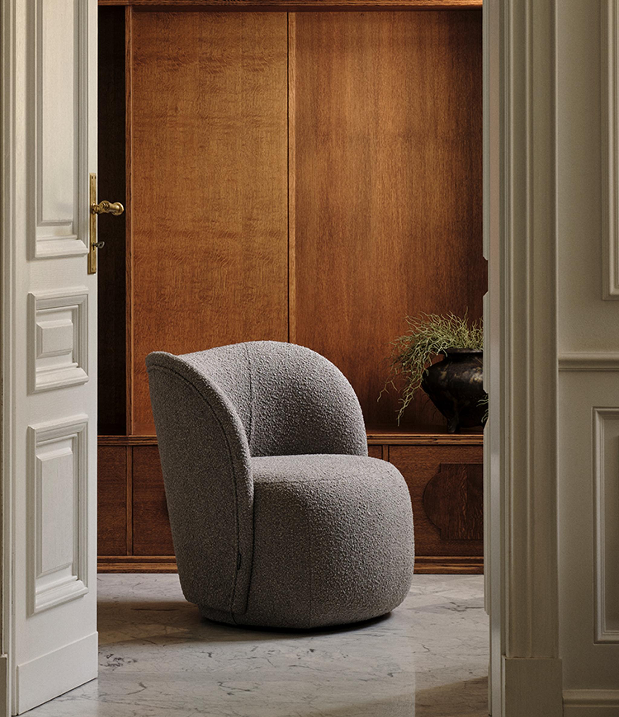 Fauteuil Micadoni aux lignes arrondies, revêtement texturé gris, mis en scène dans un intérieur chaleureux.