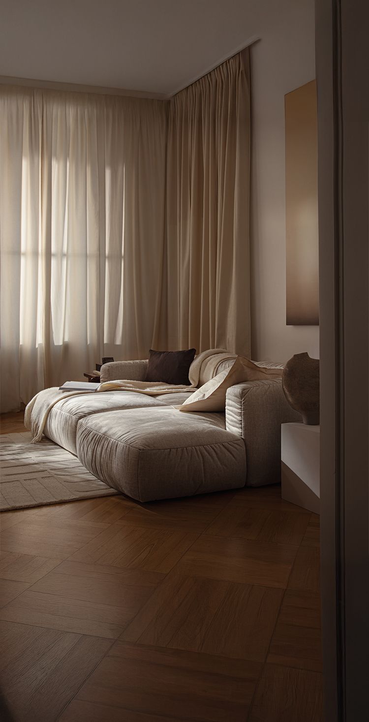 Lit Micadoni Martina en tissu avec tête de lit basse, table d’appoint et linge de lit neutre dans un intérieur classique.