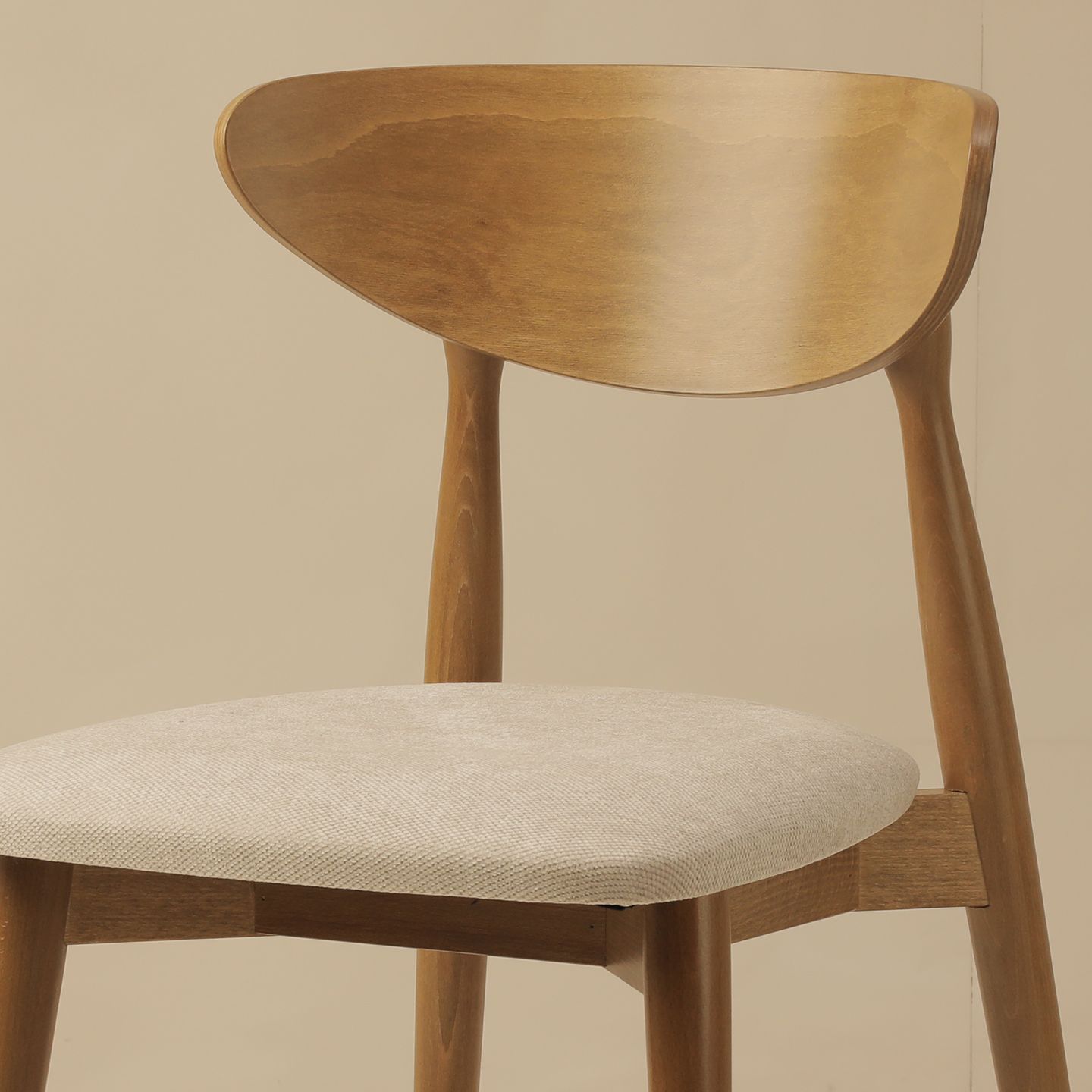Gros plan d’une chaise de salle à manger Micadoni en bois avec dossier courbé en chêne clair, baignée de lumière.