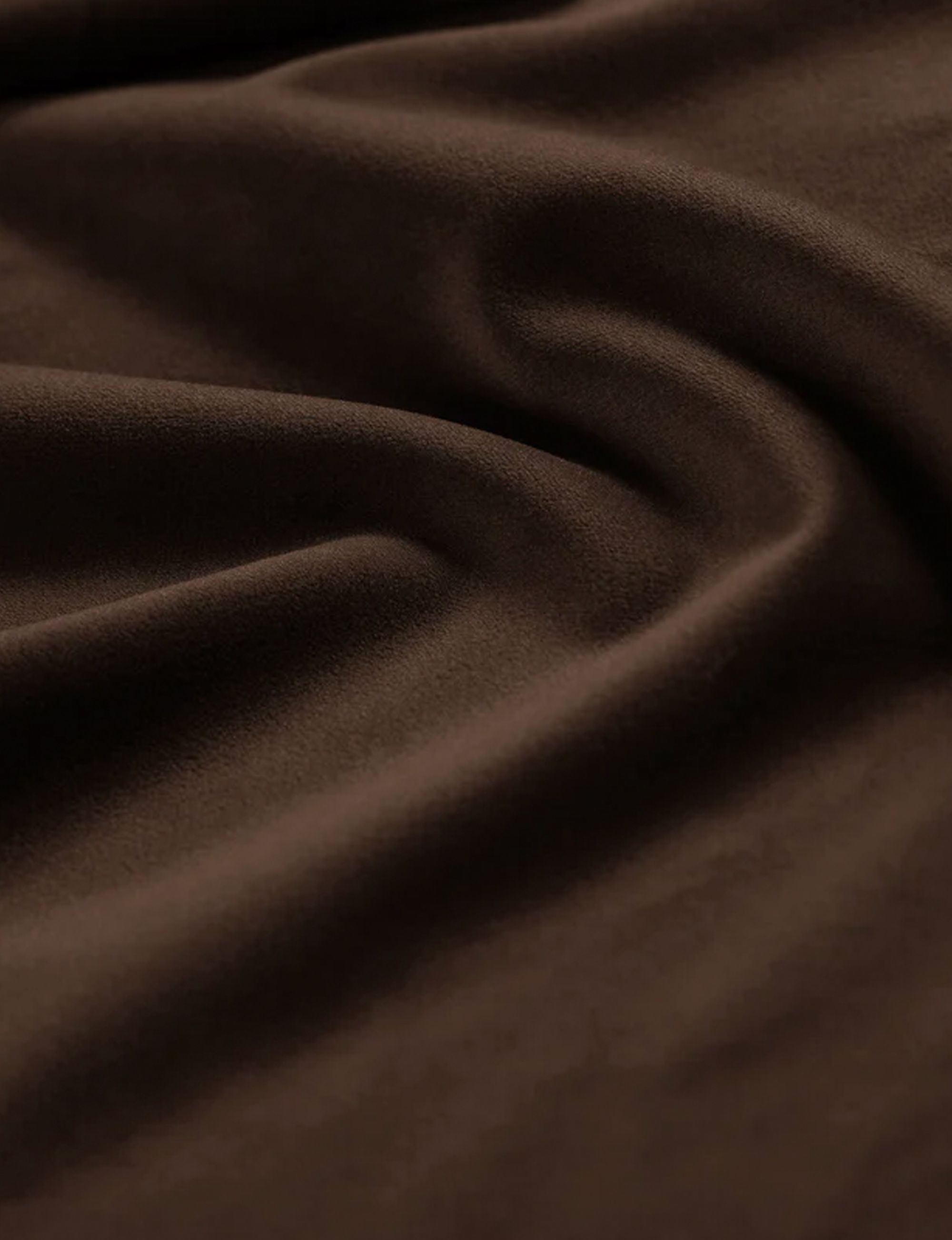 Gros plan sur le canapé Kate Micadoni, accoudoir arrondi et tissu jaune texturé sur sol neutre.