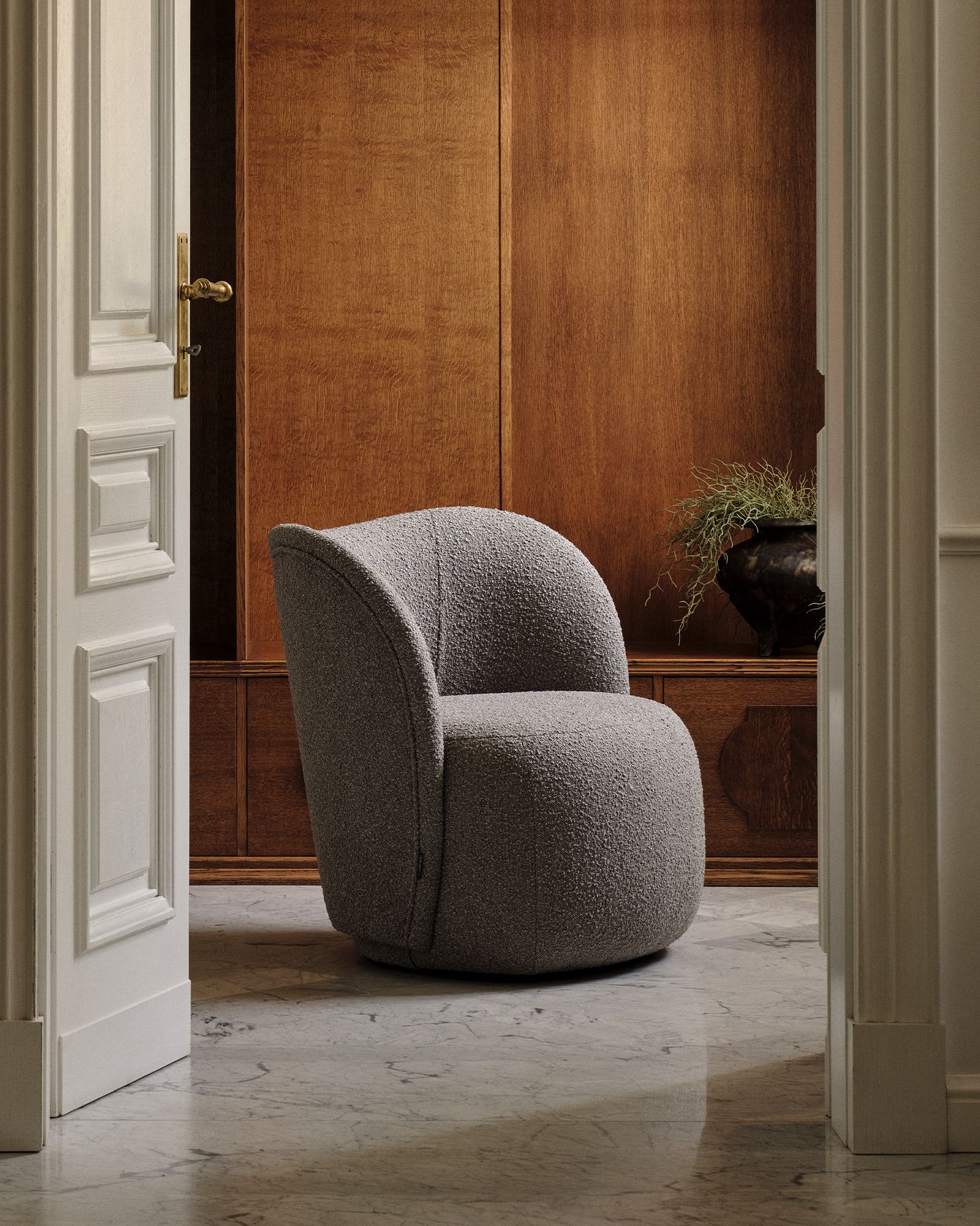 Fauteuil Micadoni aux lignes arrondies, revêtement texturé gris, mis en scène dans un intérieur chaleureux.