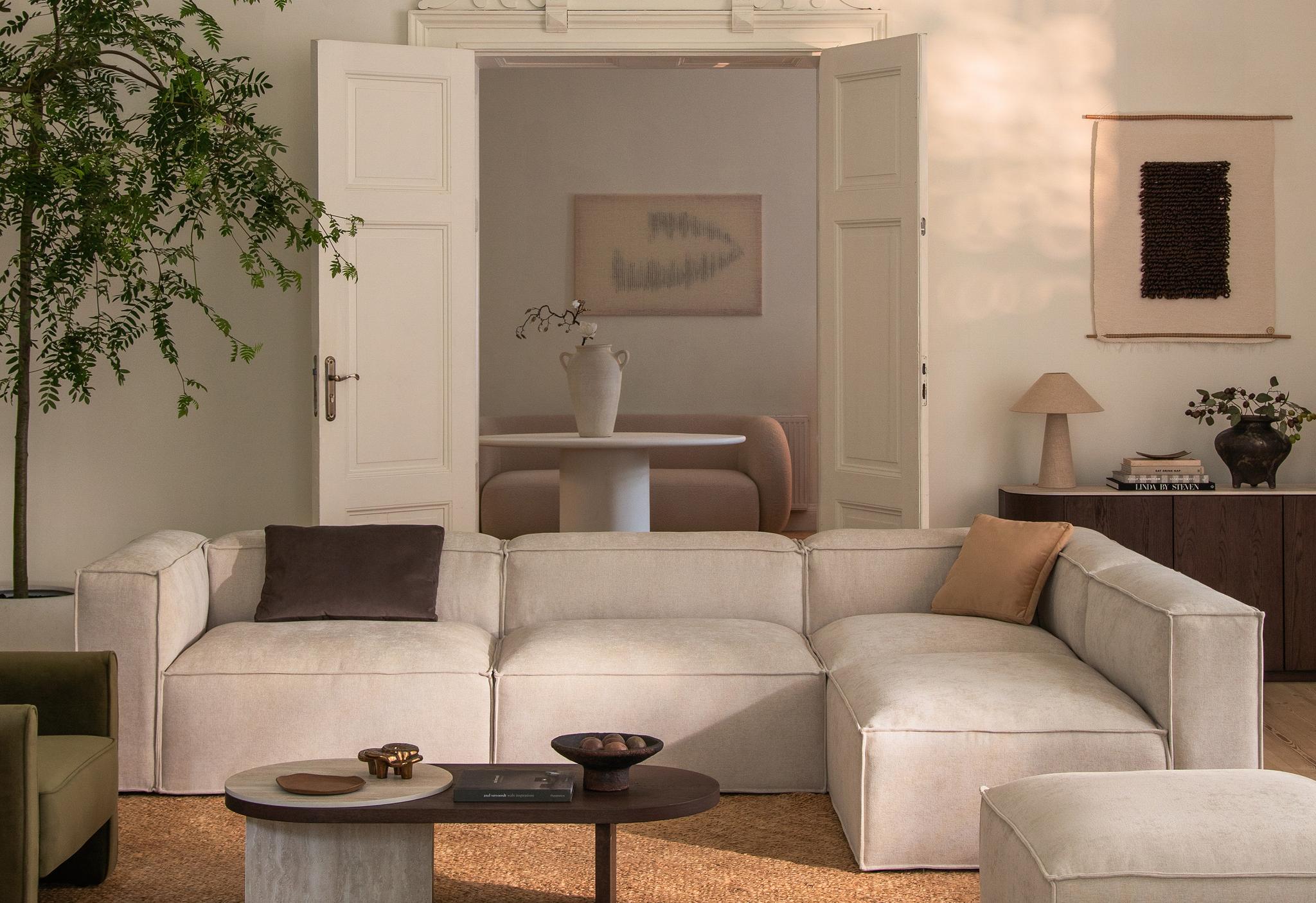 Canapé d’angle modulaire Nuria en tissu gris clair texturé avec accoudoirs droits et coussins assortis – mobilier Micadoni