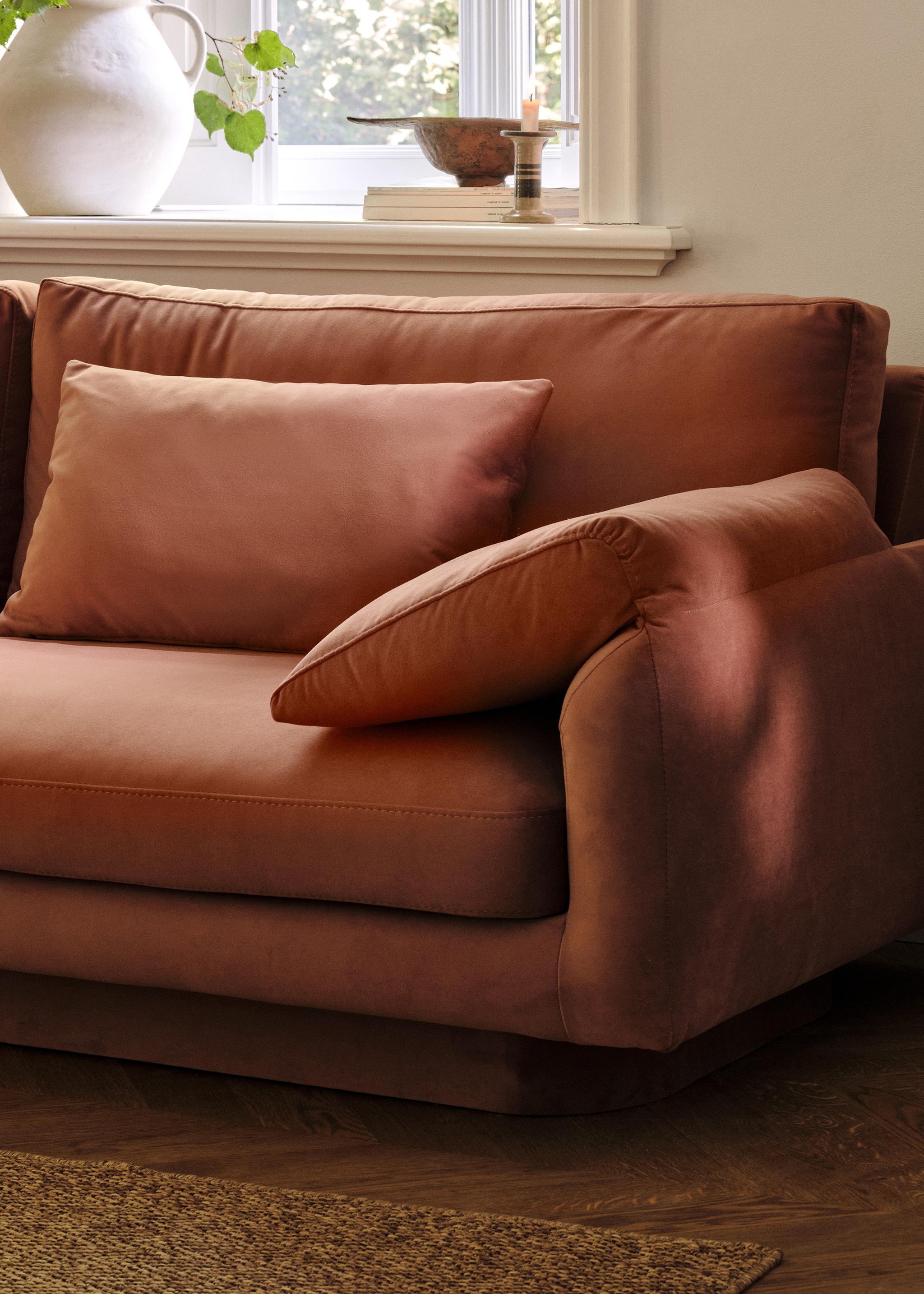 Gros plan du canapé Torino en velours couleur rouille avec accoudoirs larges rembourrés et assise profonde – mobilier Micadoni
