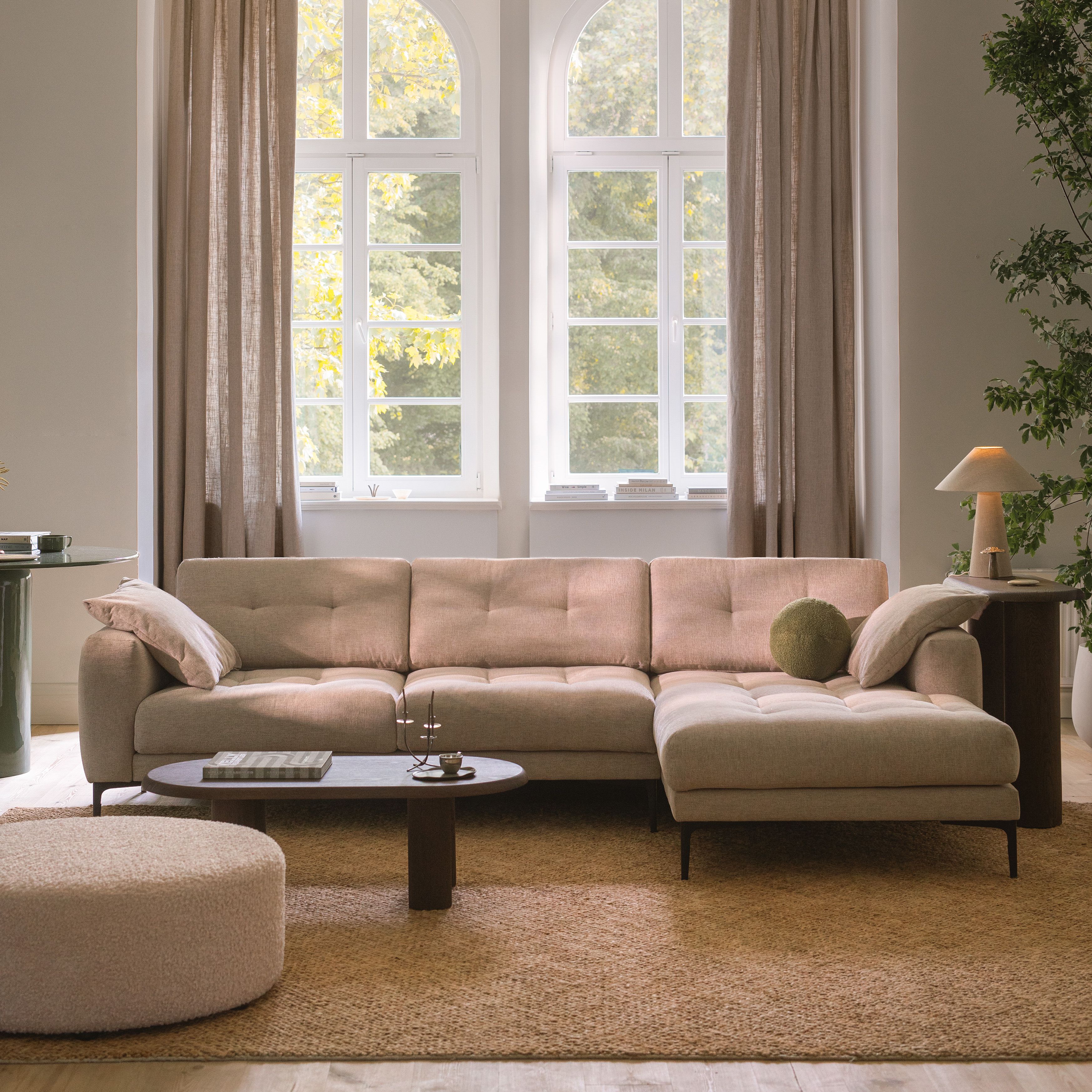 Canapé d’angle Micadoni Bemy en tissu beige, coussins capitonnés et méridienne à droite, dans un salon lumineux.