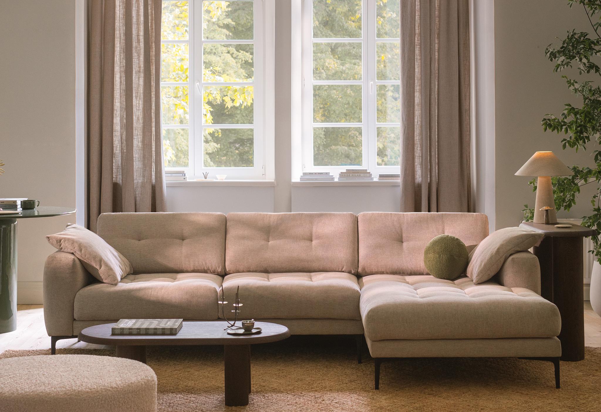 Canapé d’angle Micadoni Bemy en tissu beige, coussins capitonnés et méridienne à droite, dans un salon lumineux.