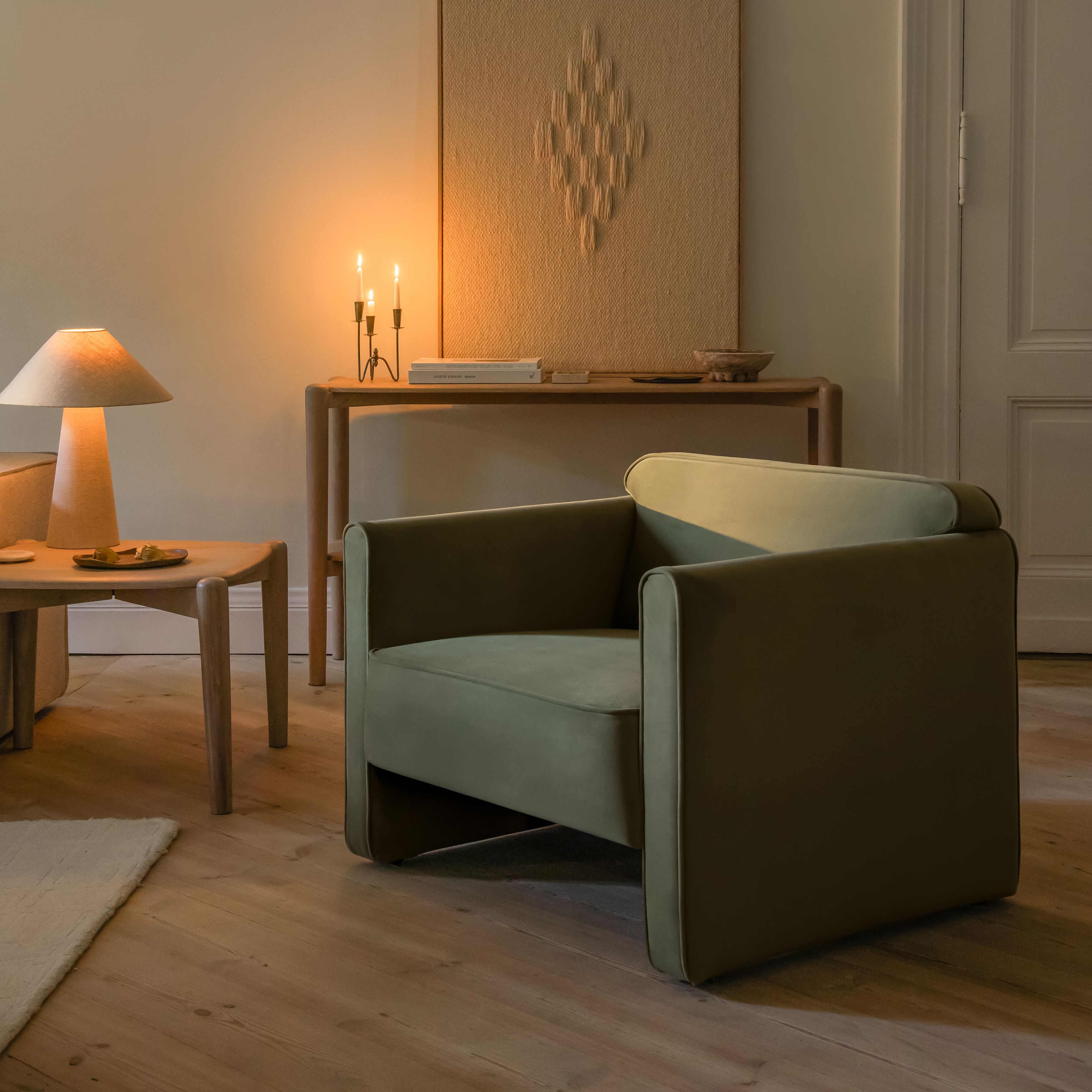 Fauteuil Abby Micadoni en velours vert olive dans un salon chaleureux avec console et lampe.