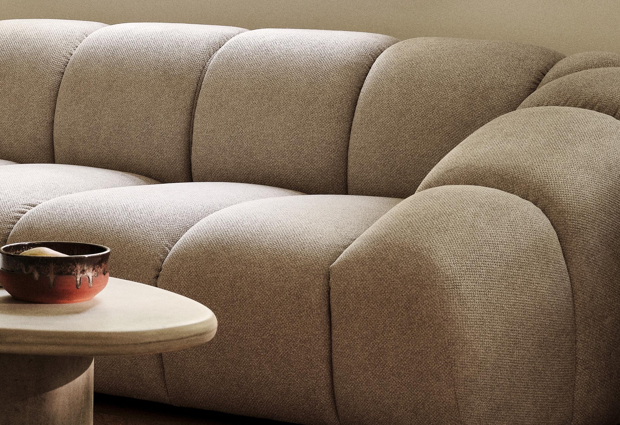 Diana sofa in beige structural fabric with rounded lines, paired with sculptural Daria stone coffee table – Micadoni furniture