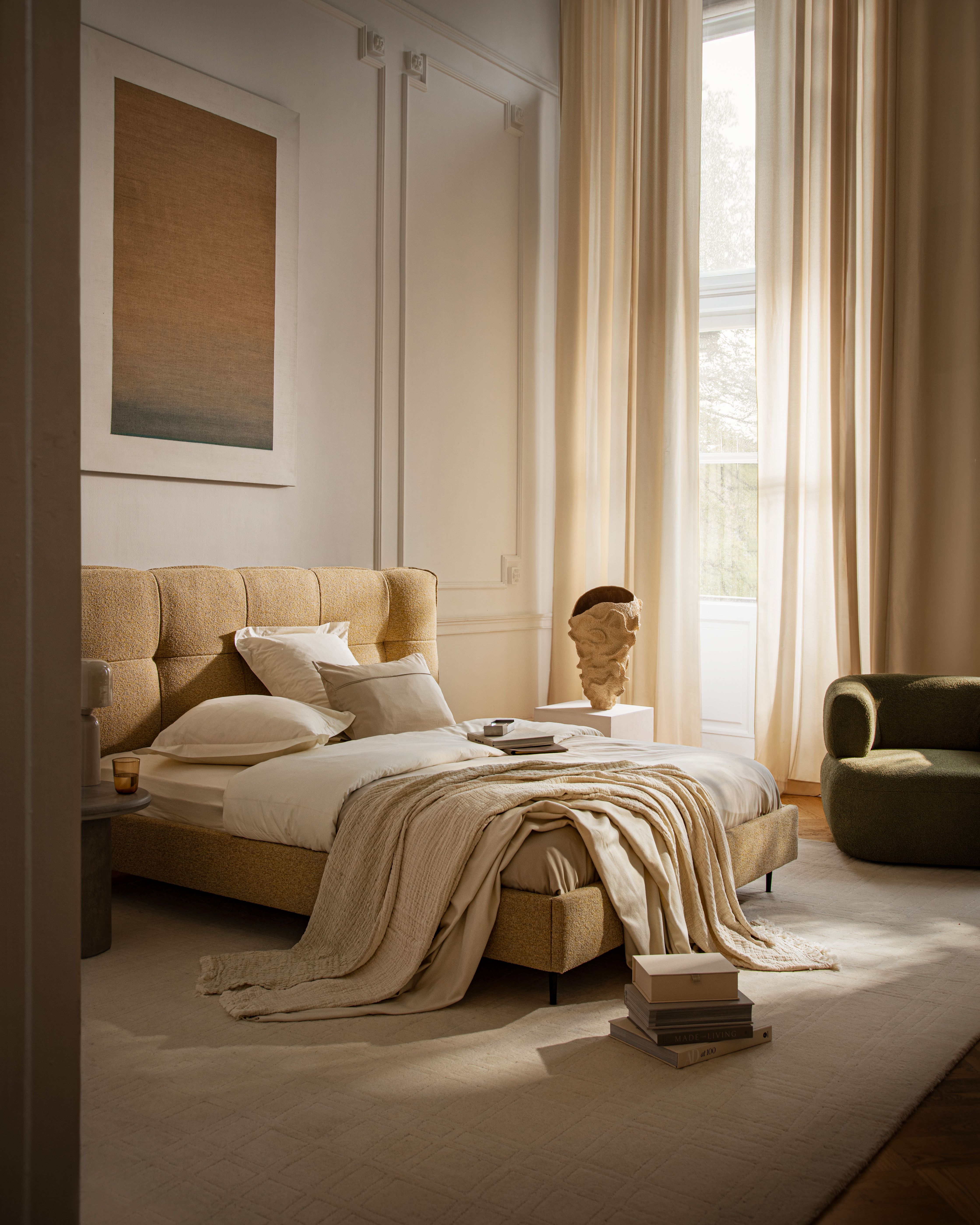 Lit Micadoni Eric avec tête de lit capitonnée à carreaux en bouclé, dans une chambre beige lumineuse.