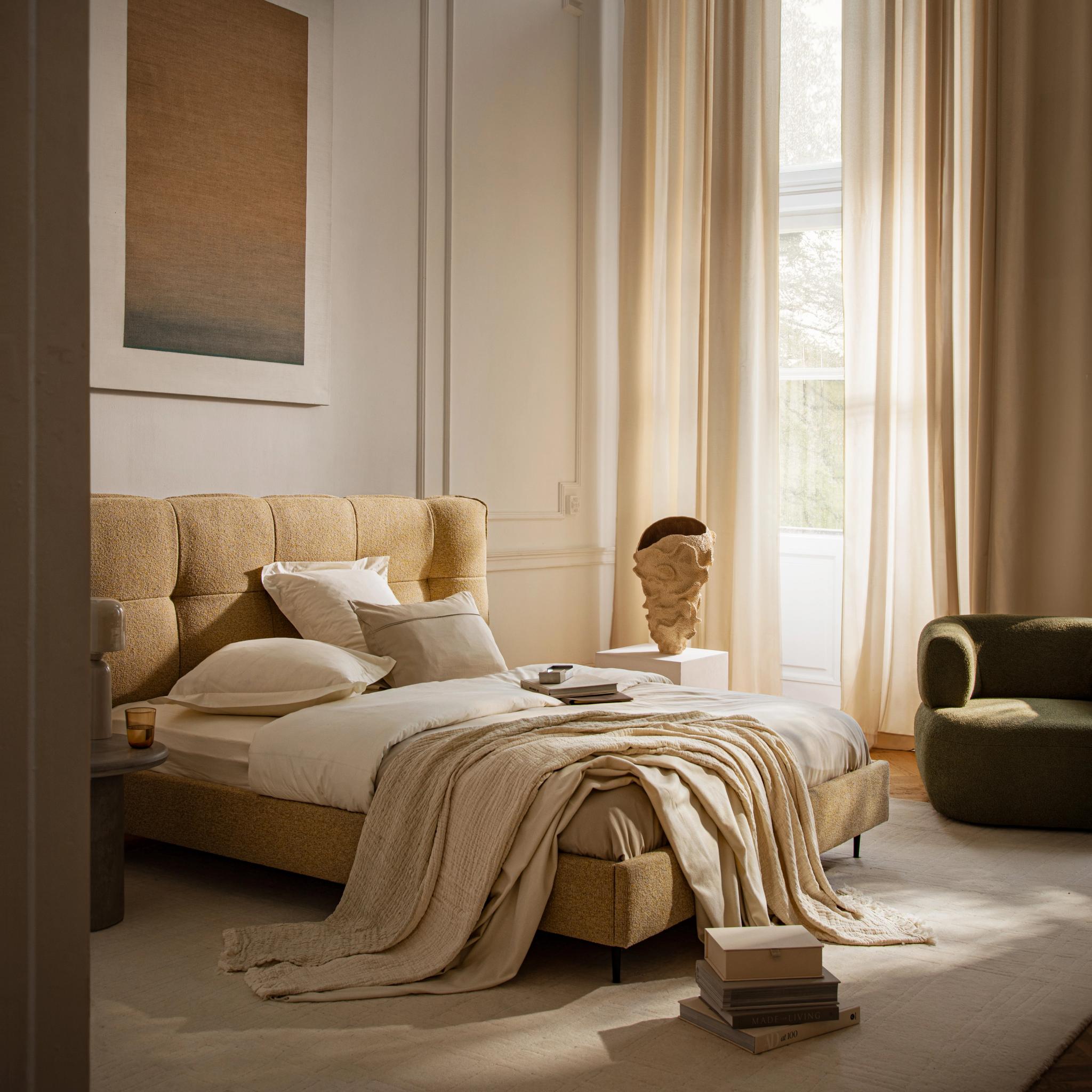 Lit Micadoni Eric avec tête de lit capitonnée à carreaux en bouclé, dans une chambre beige lumineuse.