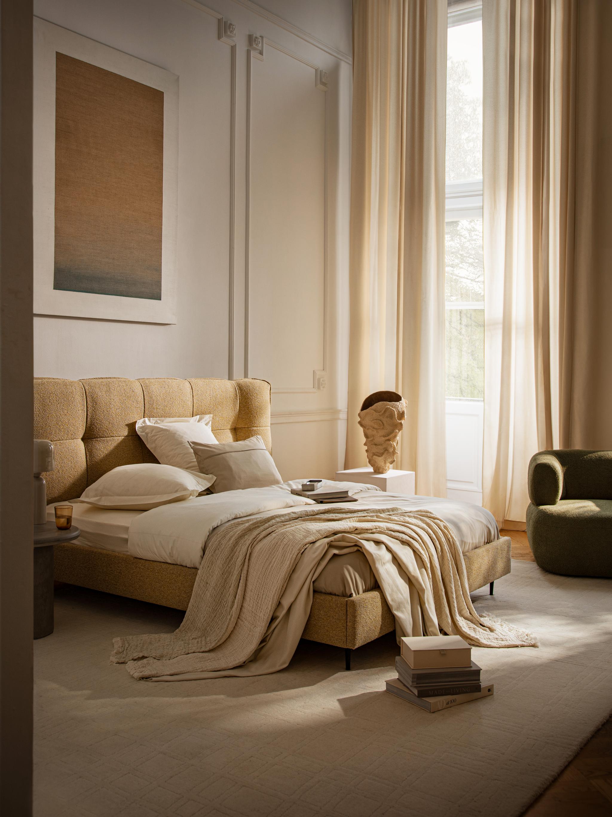 Lit Micadoni Eric avec tête de lit capitonnée à carreaux en bouclé, dans une chambre beige lumineuse.